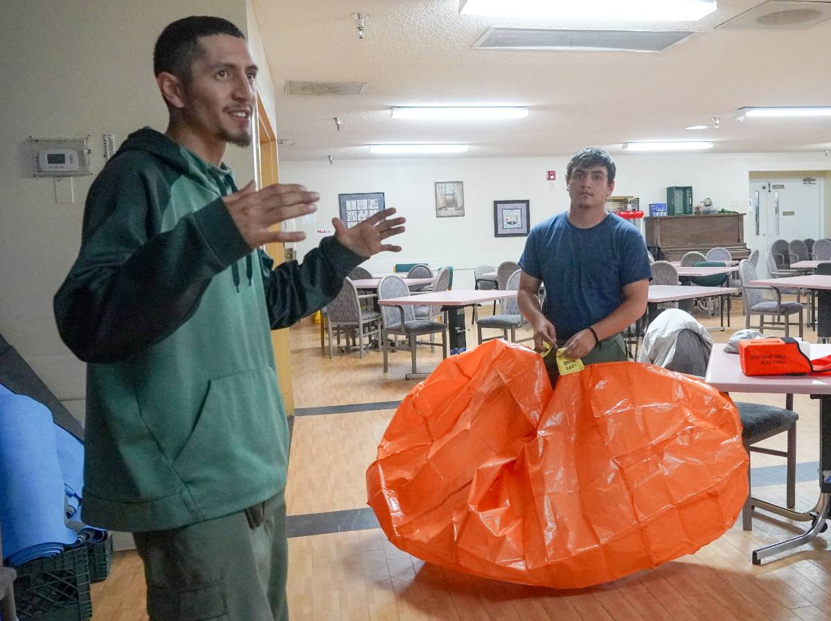 Zachary Gurule, Firefighter with the Chama State Forestry District, coaches a Wildland Firefighting course participant in how to deploy a fire shelter.