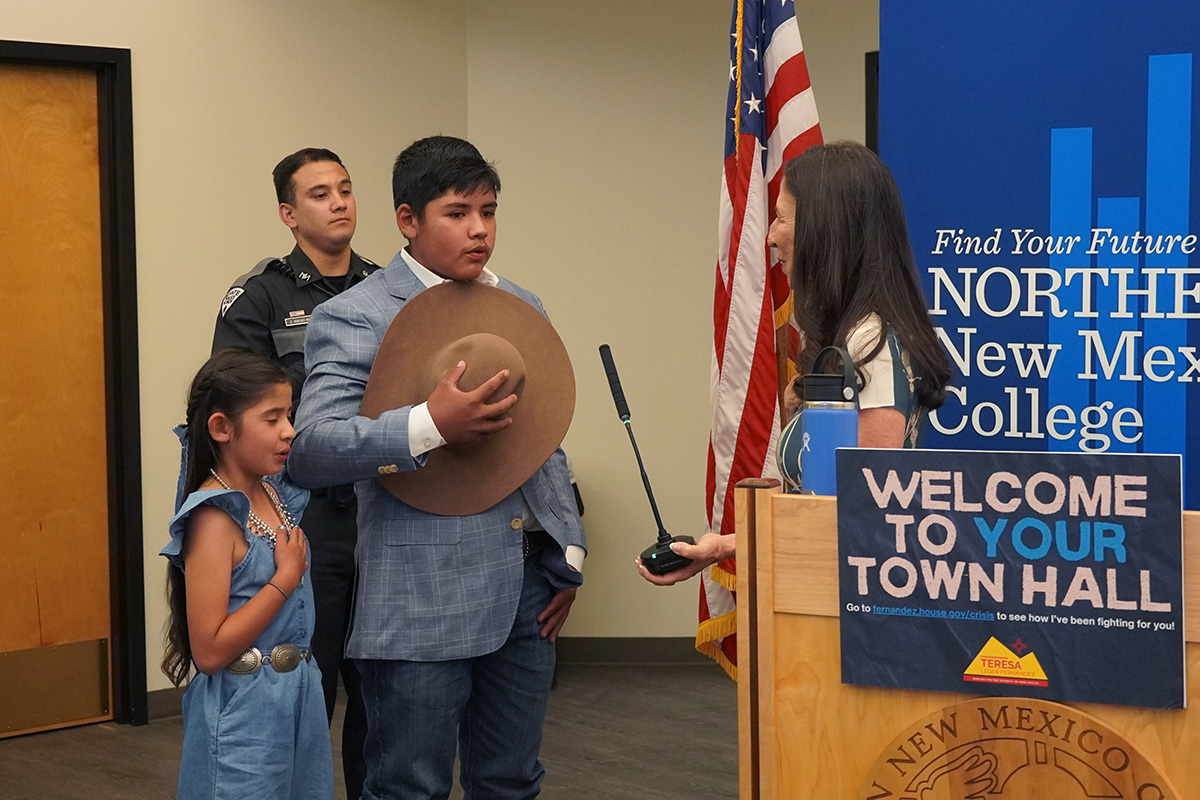 Waylan and Kinsleigh Valdez lead the Pledge of Allegiance with Congresswoman Teresa Leger Fernández next to them and a State Police in the background